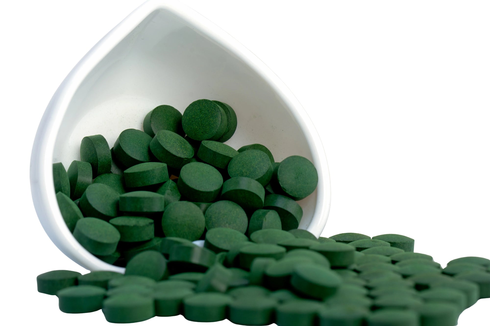 Spirulina Tabletten die in einem umgekippten Mörser liegen